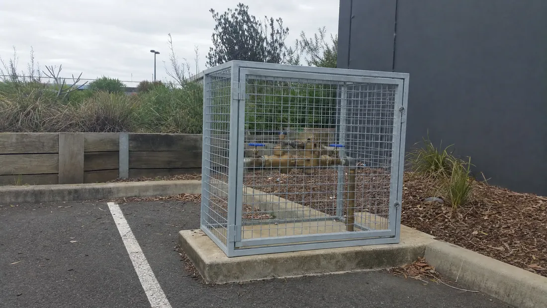 Backflow device in a cage on a commercial site